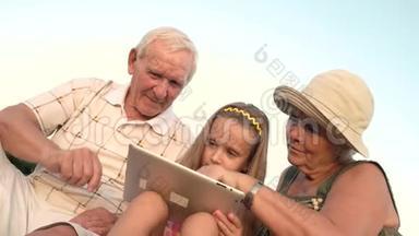 祖父母和孙女玩电脑平板电脑。